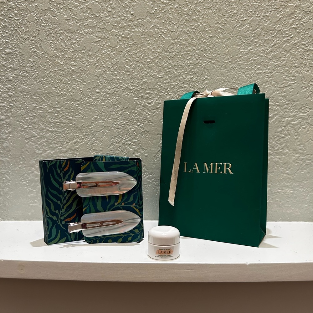 Two never used La Mer hair clips with logo green bag and mini moisturizer